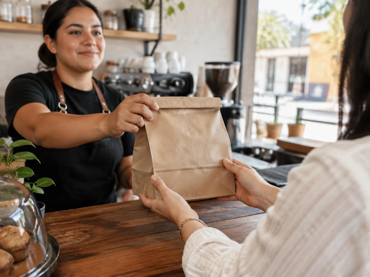 Una persona entrega una bolsa de papel en el mostrador de una cafetería